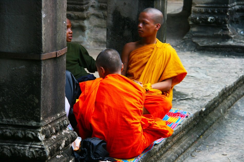 young buddhists in orange clothes near the temple