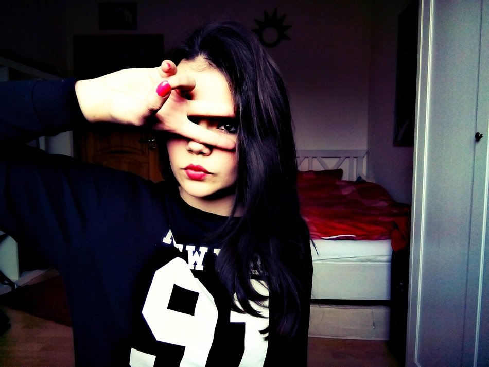 girl with dark hair makes a peace sign with her fingers