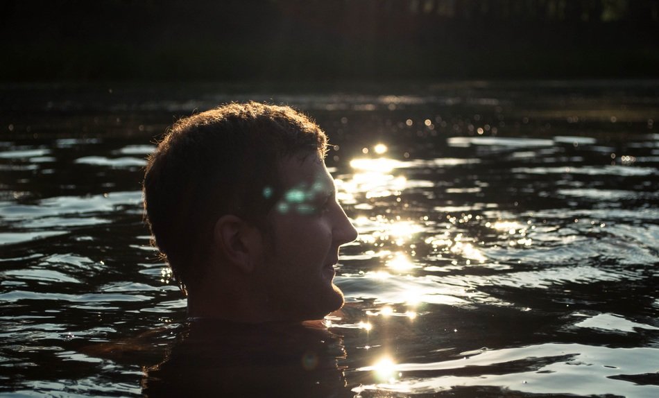 man head above water at backlight