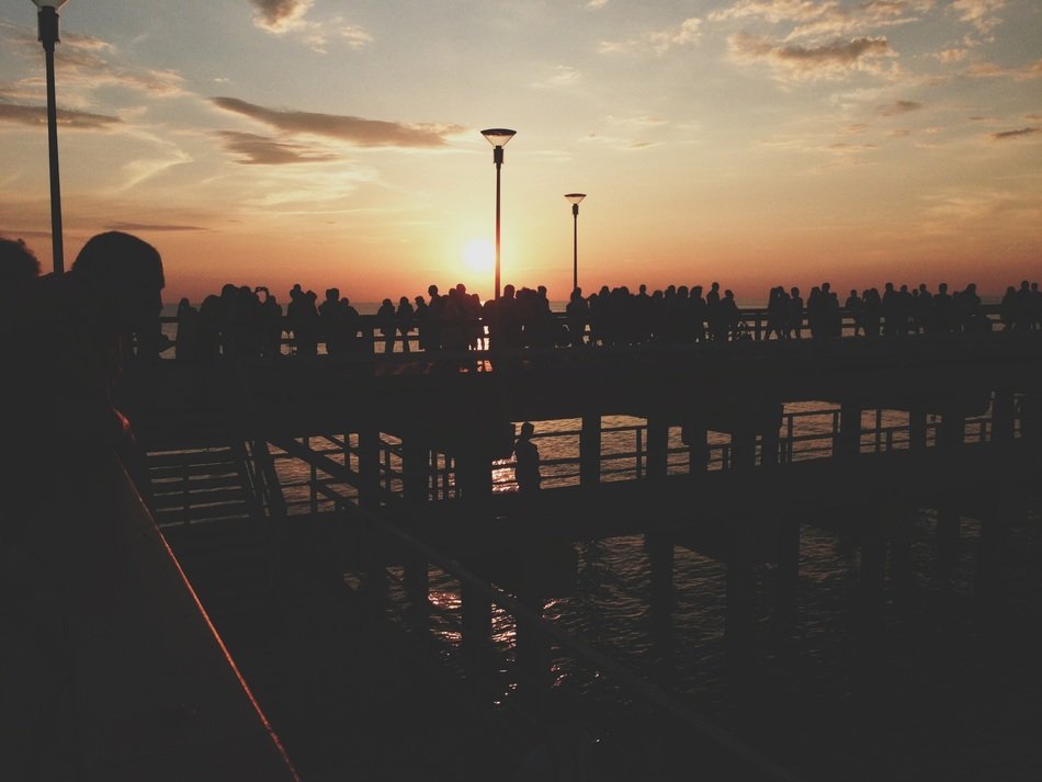 silhouettes of a crowd on the pier at sunset