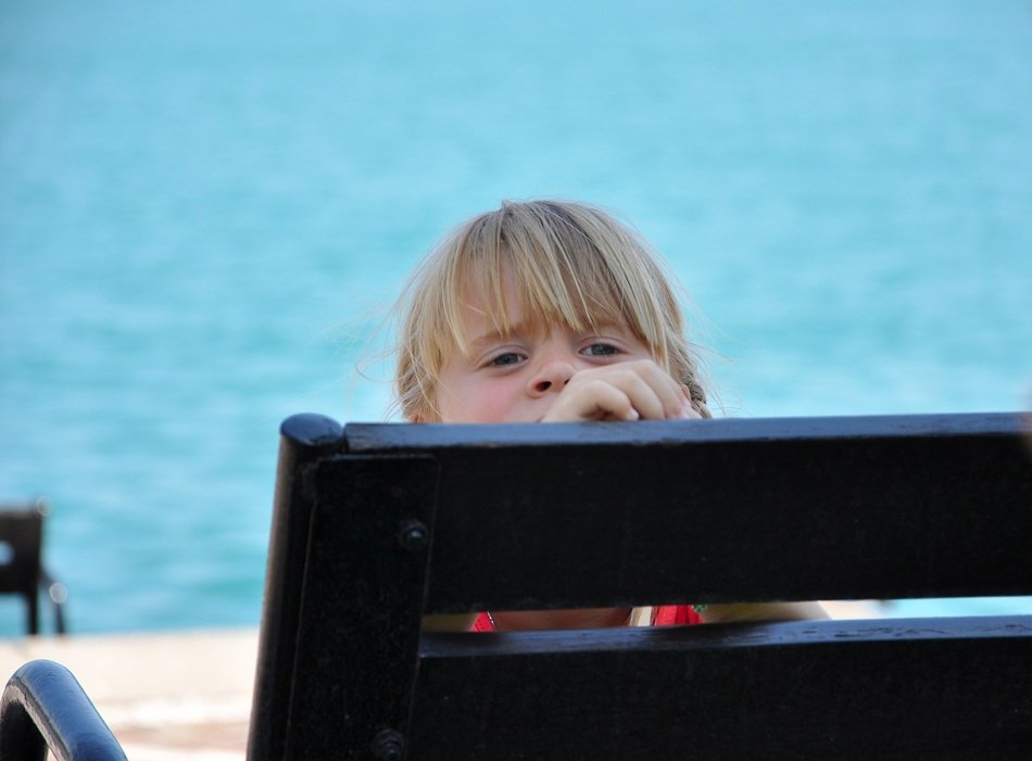 child sits behind a wooden bench