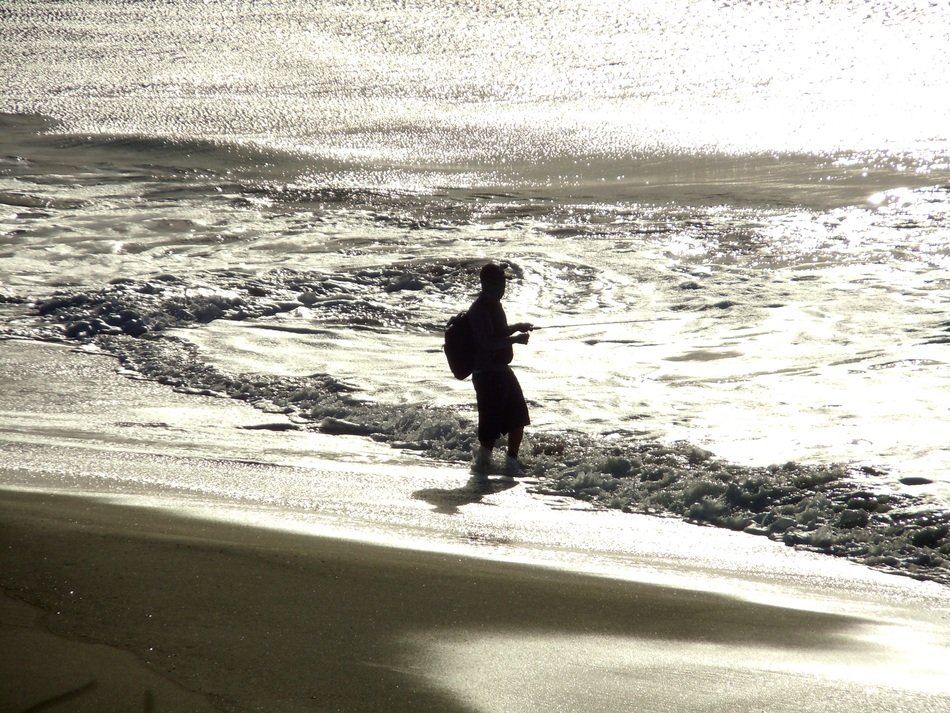 silhouette of a fisherman in the waves of the surf