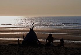 people near wigwam on the beach of the north sea