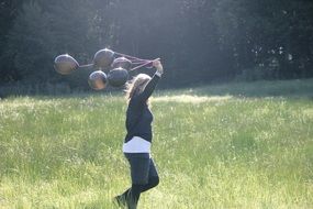girl with black balloons running by meadow
