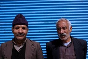Iranian men stand near the blue wall