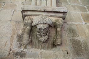 sculpture on the shoulders with a column on the facade of the building