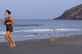 girl running on the beach with a dog