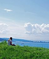 girl sitting on the green grass on the background of the sea