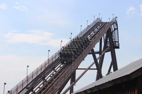 detail of roller coaster in amusement park at white cloudy blue sky