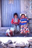 children in colorful folk costumes on street at wall, peru