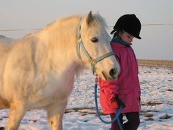 little girl near a white pony