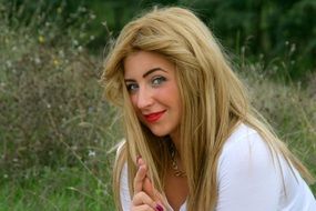 blonde girl with green eyes on a grass background