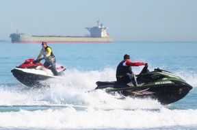 Two hydrocycles on the waves in the background of the ship