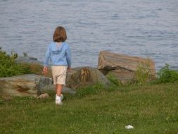 little girl on green grass near the ocean