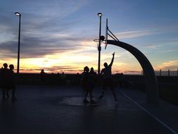 people play basketball at sunset