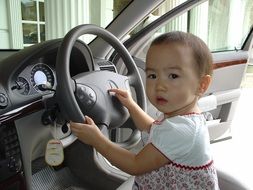 child sits at the wheel of a car in thailand