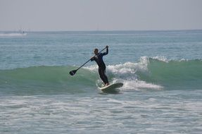 surfing with a paddle on the waves of the ocean in San Clemente, California