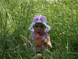 girl in panama sits in the green grass