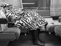 Black and white man sleeps on a train in a striped blanket