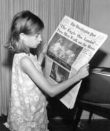 child girl reads newspaper about moon landing, vintage