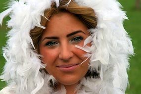 Portrait of green-eyed girl in white feathers as a snowflake