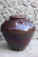 brown large jug near the stone wall