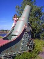 girl posing near the old gun