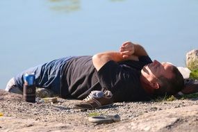 man lies on the river bank