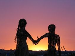 monument of couple's handshaking at sunset background