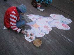 picture of the man is drawing a graffiti on a road