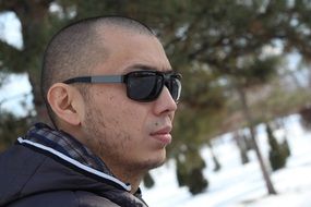 short-haired man in sunglasses against the background of a winter landscape