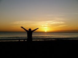Happy person is resting on the beach at sunset