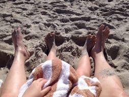 feet of an adult and child in the sand on the beach
