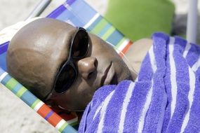 black man with glasses on a deck chair