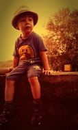 child boy sits outdoor at summer