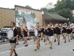 people walk along the road with drums