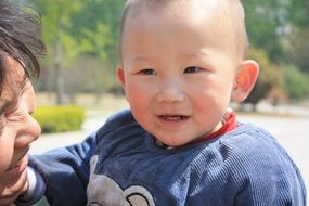 asian baby in her arms close-up on blurred background