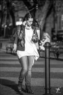 black and white photo of a girl walking down the street with iPod and earphones