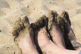 two pairs of feet in sand on beach