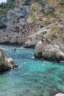 girl walking on rope between rocks over blue water