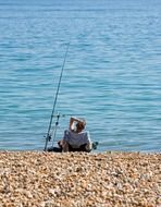 fisherman is resting on a pebble beach