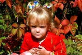 baby girl with blond hair on the background of autumn leaves