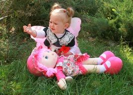 baby with a huge doll on green grass