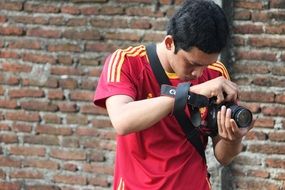 young photographer with a camera near a brick wall