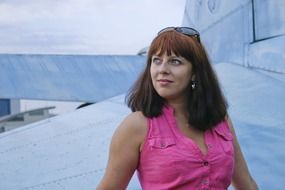 Girl in a bright pink dress on the background of an airplane