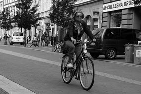 black and white photo of a man on a bicycle down the street