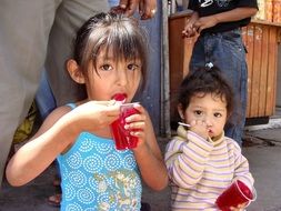 girls eating red fruit jelly in cups in Peru