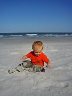 little boy playing in the sand on the beach