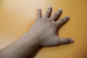 man hand lays on yellow surface