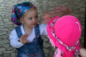 Girl looks at the pink doll through a window
